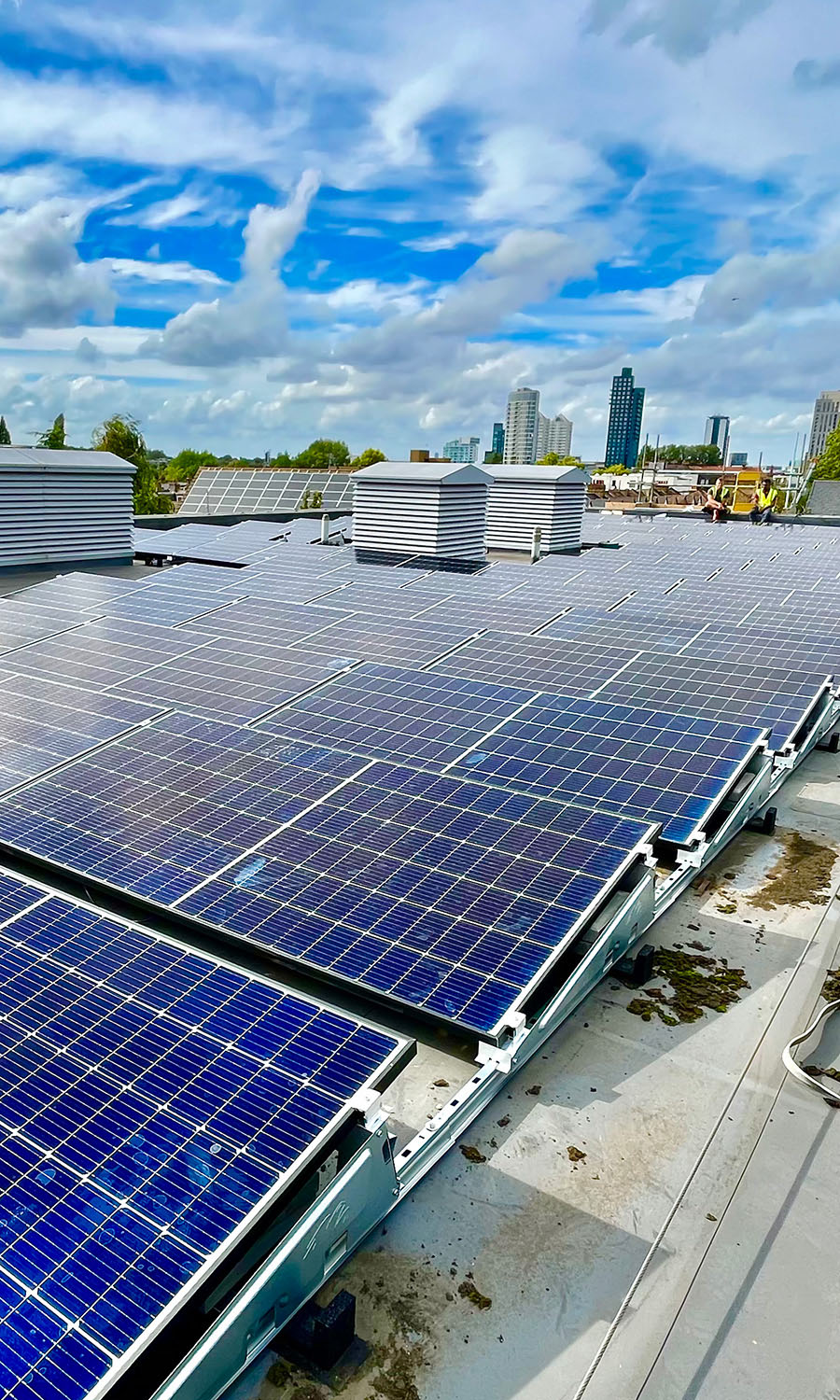 Solar panels on a commercial roof with city in the background