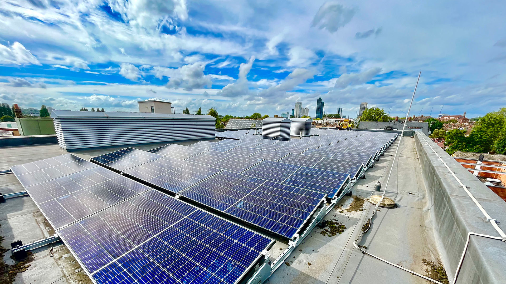 Solar panels on a commercial roof with city in the background