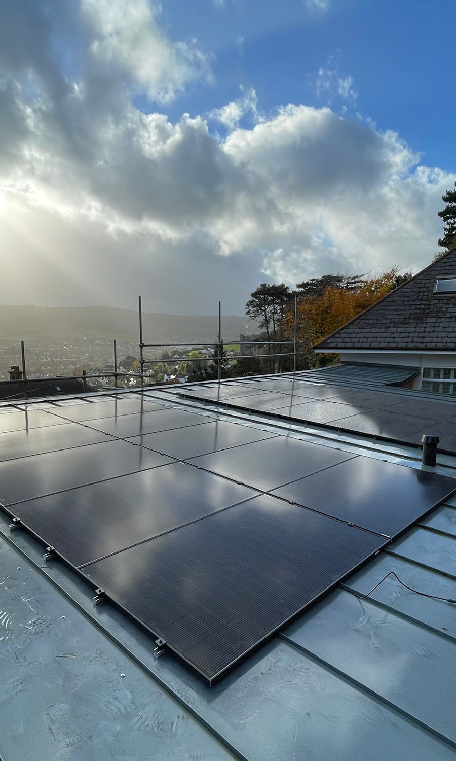 Solar panels on a roof with surrounding countryside in the background