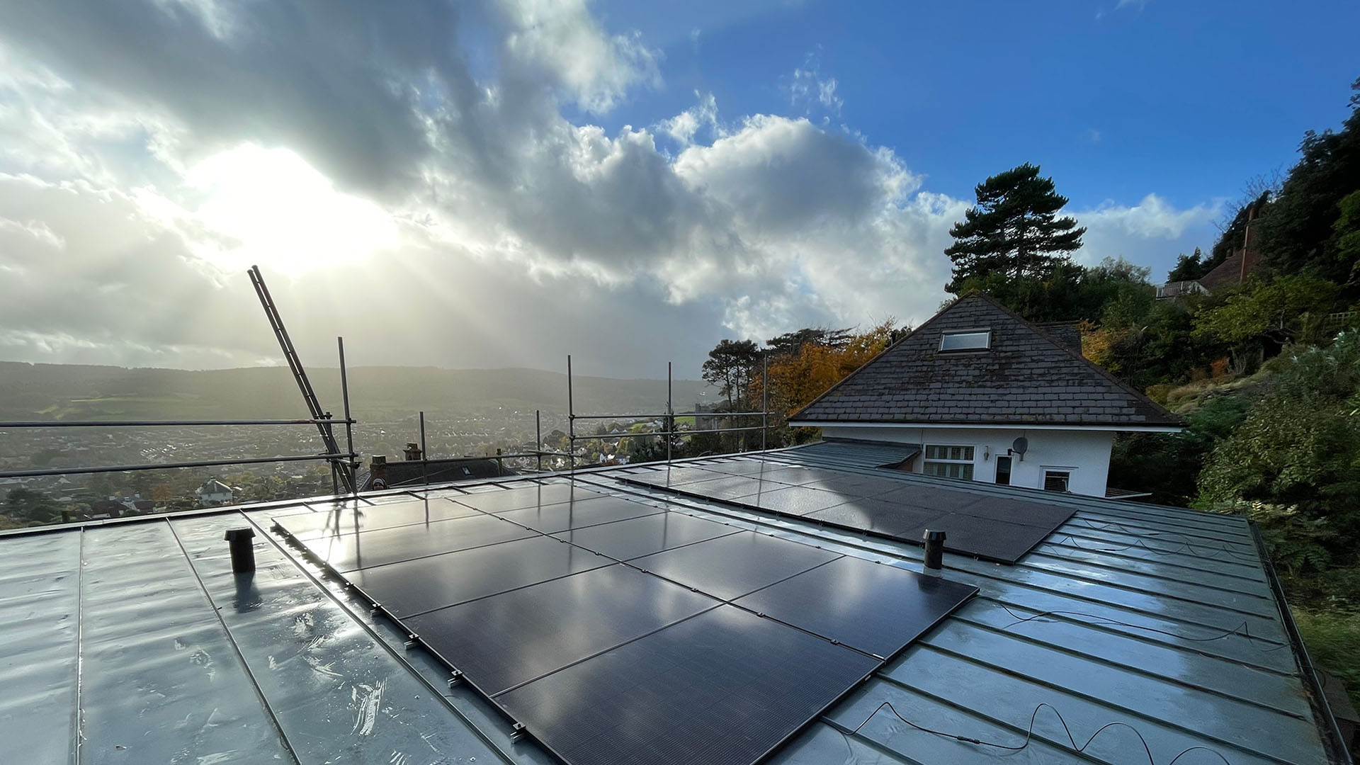 Solar panels on a roof with surrounding countryside in the background