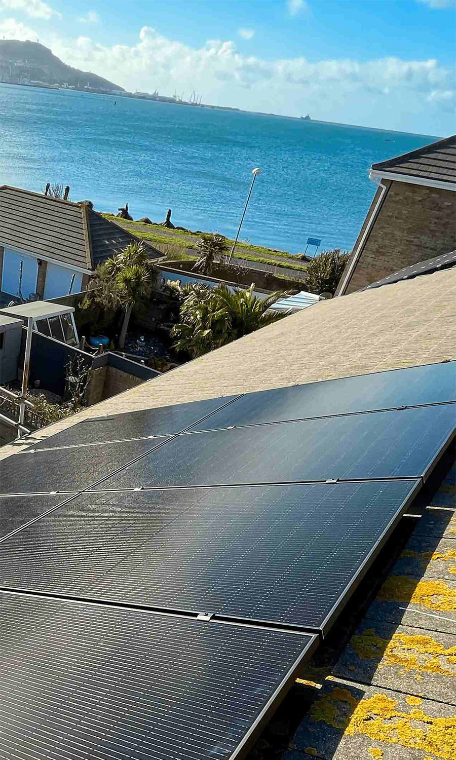 Solar panels on a roof with ocean in the background